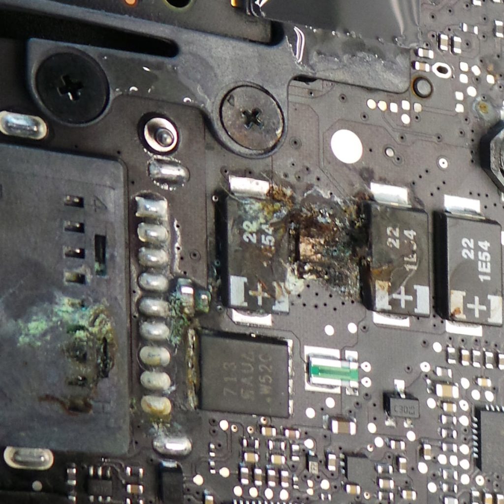 Water damaged macbook pro logic board showing corrosion and short circuit before repair