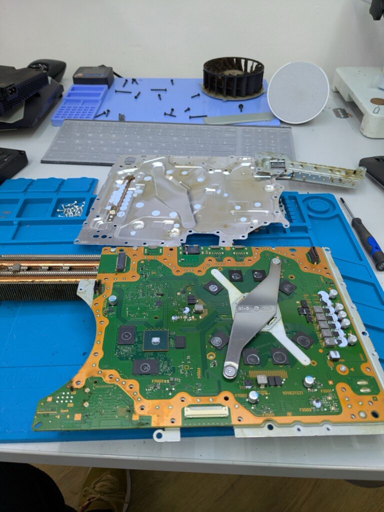 PlayStation 5 Slim fully stripped down on the bench with the logic board, cooling stack, fan and chassis shielding all separated