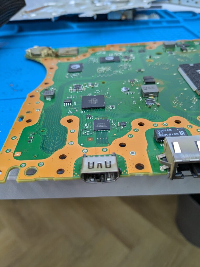 Closeup of the PlayStation 5 Slim logic board rear edge showing the HDMI, USB and LAN ports on the bare PCB ready for the port replacement